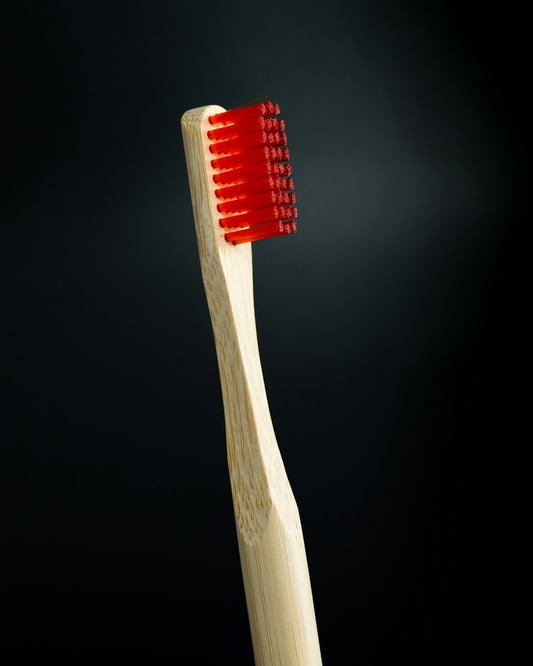 a wooden toothbrush with red bristles on a black background