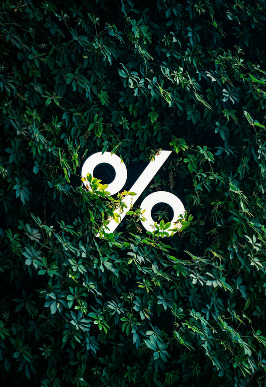 A white percentage sign logo surrounded by green leaves.