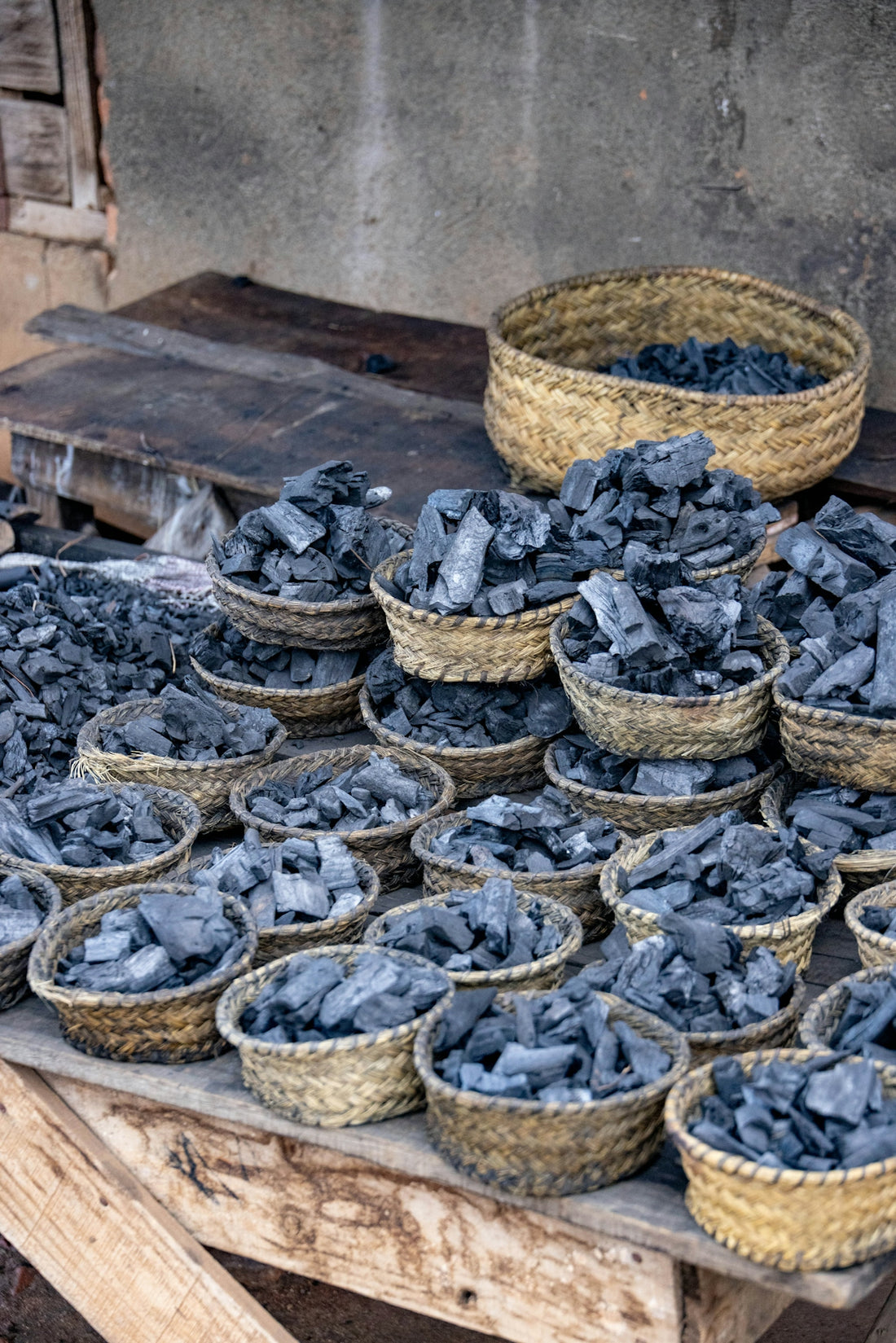 Many small baskets filled with charcoal on a wooden table.
