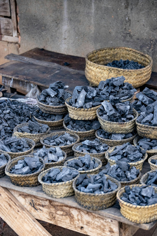 Many small baskets filled with charcoal on a wooden table.